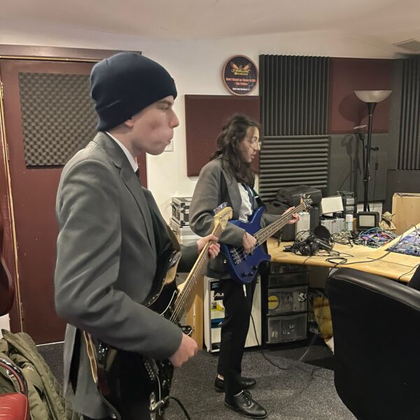 Two students in a recording studio playing guitars.